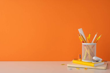 Düzenli ve minimal biçimde kırtasiye malzemesi olan parlak renkli bir çalışma alanı. Canlı turuncu tonlar ve yaratıcı ve üretken bir öğrenme ortamı yaratmak için gerekli çalışmalar.