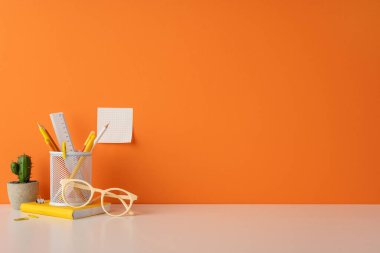 Kırtasiye ürünleri, küçük bir kaktüs ve canlı turuncu arkaplan içeren şık bir çalışma alanı tasarımı. Verimliliği ve yaratıcılığı organize ve cezbedici bir etikle temsil etmek için harika.