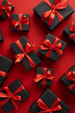 Kırmızı arkaplanda kırmızı kurdeleli siyah hediye kutularının dikey görüntüsü