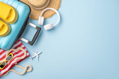 Yaz tatili için ayarlanmış bavul, kulaklık ve güneş gözlüğü de dahil olmak üzere seyahat için gerekli malzemeler.