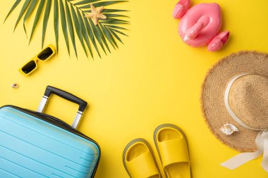 Düz kompozisyonda bavul, şapka, güneş gözlüğü ve sarı renkte yüzme malzemeleri vardı. Canlı yaz teması