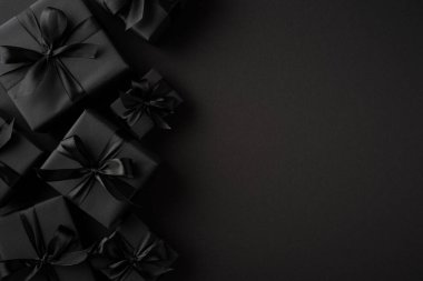 Karanlık hediye kutuları ve siyah saten kurdeleler karamsar, minimalist bir zemin üzerinde ustalıkla düzenlenmiş sofistike bir atmosfer yaratıyorlar..