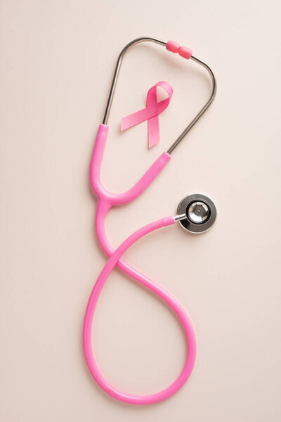 Pink vertical stethoscope alongside a pink ribbon, symbolizing health awareness and breast cancer support