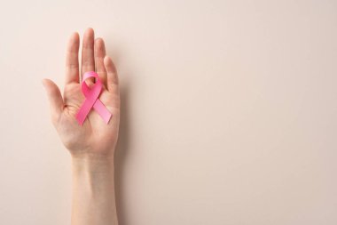 Bir el, göğüs kanseri farkındalığının evrensel sembolünü temsil eden pembe kurdeleyi ve erken teşhis savunuculuğunu, hastalıktan etkilenenler için dayanışmayı ve umudu destekliyor.