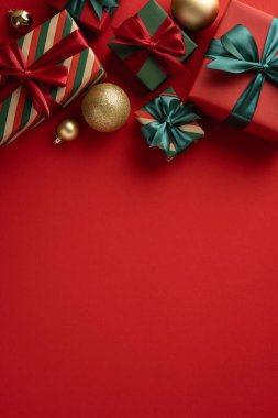 Kırmızı arka planda düzenlenmiş kurdele ve süslemeleri olan dikey Noel hediyeleri şenlikli bir ortam yaratıyor.