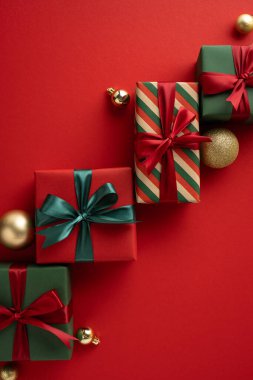 Yay ve bayram süsleriyle süslenmiş hediye kutuları dikey kırmızı şenlik yüzeyi, Noel neşesini ve kutlamaları simgeliyor.