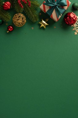 Şenlikli düzenlenmiş dikey Noel süsleri ve yeşil bir arkaplanda sergilenen bir hediye.