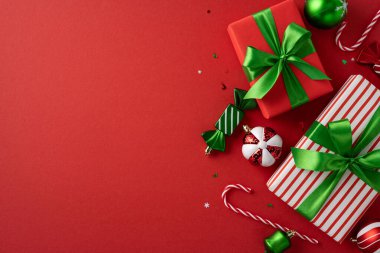 Yeşil kurdeleler, süsler ve baston şekerlerle sarılmış Noel hediyelerinin yer aldığı şenlikli bir görüntü. Bayram temalı tasarımlar ve mevsimin neşeli ruhunu kutlamak için mükemmel.