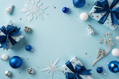 Zarif paketlenmiş hediyeler, parlak mavi ve gümüş süsler ve mükemmel bir Noel atmosferi yaratan Noel dekorunun yer aldığı şenlikli bir sahne.