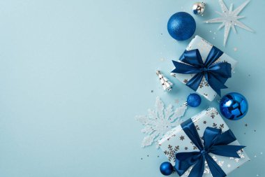 Mavi fiyonklarla süslenmiş zarif hediye kutuları. Yanında da şenlikli gümüş ve mavi süsler var.