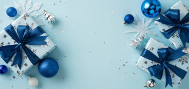 Mavi kurdeleler, dekoratif süsler, kar taneleri ve parlak ve şenlikli bir düzende süslemeli Noel temalı hediye kutularının yer aldığı Noel temalı kompozisyon