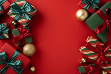 Noel hediyeleri, dekoratif ambalajlar ve parlak kırmızı bir zemin üzerine dizilmiş altın mücevherler.