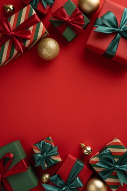 Noel hediyeleri ve altın süsler dikey kırmızı bir yüzeye dizilmiş, bayram neşesi yayıyor.