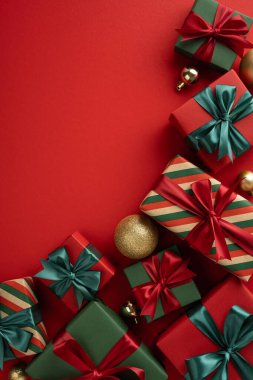 Kırmızı arka planda fiyonklu ve süslü bayram hediyeleri şenlikli bir cazibe yaratıyor.