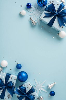 Açık mavi arkaplanda süsler, hediyeler ve kar tanelerinin yer aldığı şenlikli mavi bir temalı Noel dikey süslemeleri