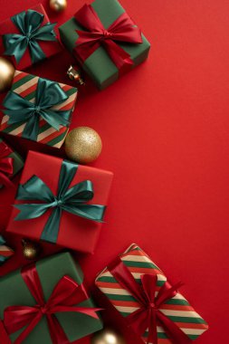 Renkli paketlenmiş Noel hediyeleri canlı kırmızı bir arka planda şenlikli dikey dekorasyonlarla düzenlenmiş. Bayram kutlamaları, hediye verme ve şenlik sezonu tasarımları için mükemmel.