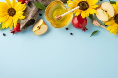 Elma, bal, ayçiçeği ve nar. Rosh Hashanah için mavi bir arka planda dizilmiş.