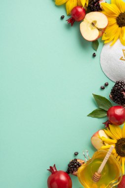 Geleneksel Rosh Hashanah ürünlerinin canlı bir görüntüsü. Yeşil arka planda elma, nar, bal ve ayçiçekleri de dahil.