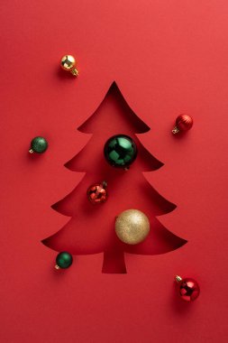 Renkli süslemelerle süslenmiş bir Noel ağacının yer aldığı dikey kırmızı bir arkaplan.