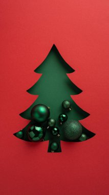 Şenlikli kırmızı ve yeşil renk paletine karşı hazırlanmış zarif yeşil süsler ve takılarla dolu bir Noel ağacı kesimi içeren yaratıcı dikey bayram tebrik kartı tasarımı