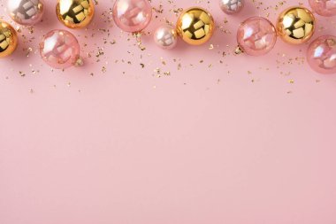 A soft pink backdrop showcases gold and pink ornaments with metallic confetti, creating a chic holiday scene ideal for seasonal promotions, greeting cards, and festive campaigns