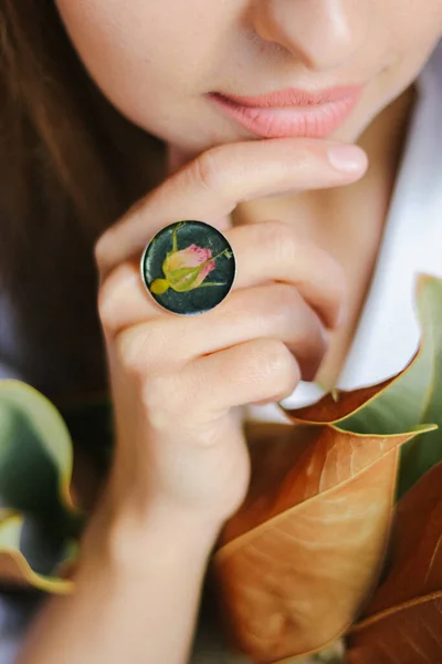 A closeup of a girls hand with ring, handcrafted ring with dried flowers