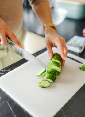 Mutfakta salatalık kesen kadın, yakın plan.