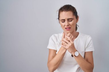 Güzel esmer kadın izole edilmiş arka planda duruyor. Ellerinde ve parmaklarında ağrı, eklem iltihabı var. 