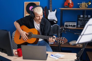 Genç beyaz müzisyen müzik stüdyosunda klasik gitar çalıyor.