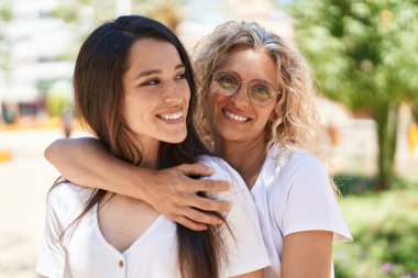 Two women mother and daughter hugging each other at park