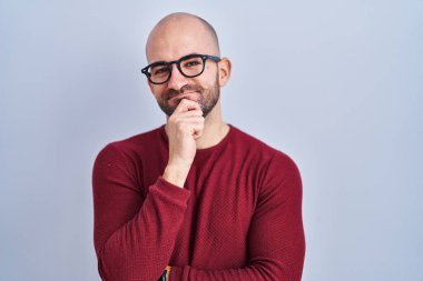 Beyaz arka planda duran sakallı, gözlüklü genç adam kameraya kendinden emin bir şekilde bakıyor kolları çapraz ve çenesi açık gülümsüyor. Olumlu düşünmek. 