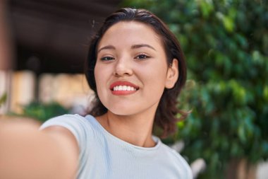 Young hispanic woman smiling confident making selfie by camera at street