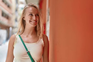 Young blonde woman smiling confident looking to the side at street