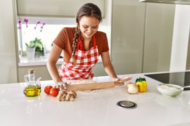 Genç, güzel, İspanyol bir kadın. Mutfakta kendine güvenen hamur pizzası.