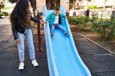 Mother and son playing on slide at park