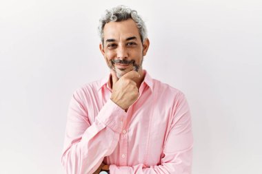 Orta yaşlı İspanyol bir adam izole edilmiş arka planda duruyor. Kameraya kollarını kavuşturup gülümseyerek ve çenesini kaldırarak bakıyor. Olumlu düşünmek. 