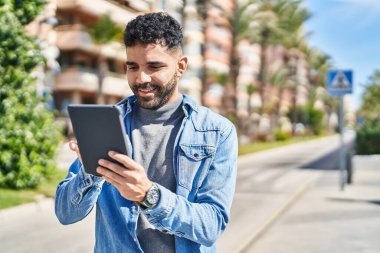 Sokakta dokunmatik ped kullanan, kendine güvenen İspanyol genç adam.