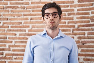 Young hispanic man standing over brick wall background depressed and worry for distress, crying angry and afraid. sad expression. 