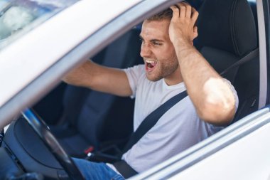 Young caucasian man stressed driving car at street