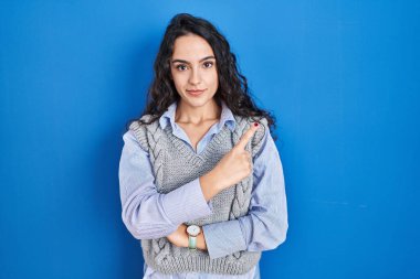 Mavi arka planda duran genç esmer kadın, elini yana uzatarak reklamını yapıyor, ciddi ve sakin bir yüz ifadesi var. 