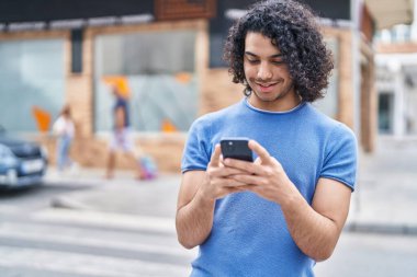 Sokakta akıllı telefon kullanan, kendine güvenen genç Latin adam.