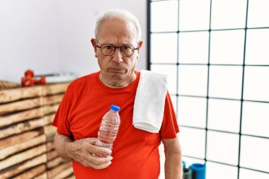 Spor kıyafetleri ve havluyu kuşkucu ve gergin bir şekilde giyen son sınıf öğrencisi sorun yüzünden surat asıyor. negatif kişi. 