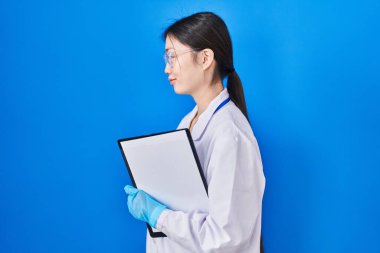 Laboratuvarda çalışan Çinli genç bir kadın profilini rahatlatmak için doğal bir yüz ve kendine güvenen bir gülümseme çiziyor.. 