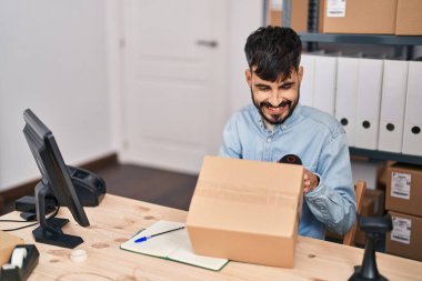 Young hispanic man ecommerce business worker scanning package at office