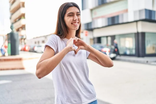 年轻美丽的惊慌失措的女人微笑着 自信地用手在街上做着心形 — 图库照片