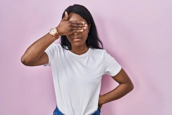 stock image African young woman wearing casual white t shirt covering eyes with hand, looking serious and sad. sightless, hiding and rejection concept 