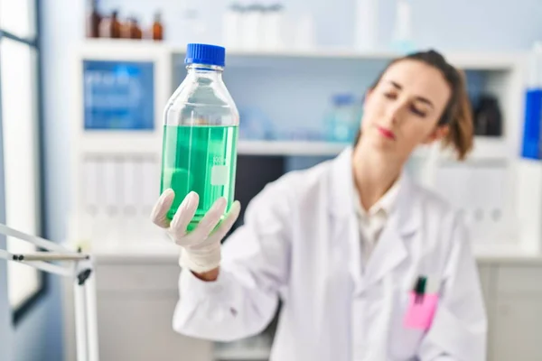 Mujer Joven Vistiendo Científico Uniforme Sosteniendo Botella Con Líquido Laboratorio —  Fotos de Stock
