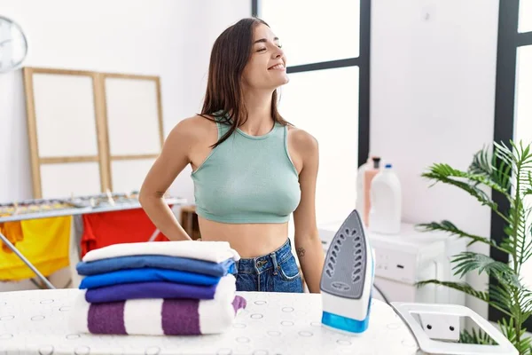Young Hispanic Woman Ironing Clothes Laundry Room Looking Away Side — Fotografia de Stock