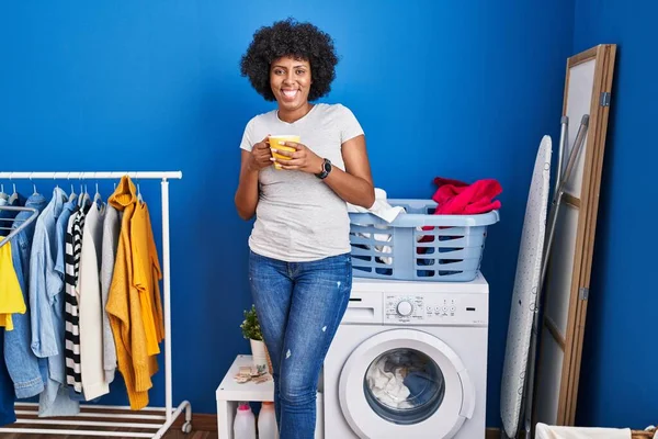 African American Woman Drinking Coffee Waiting Washing Machine Laundry Room — ストック写真
