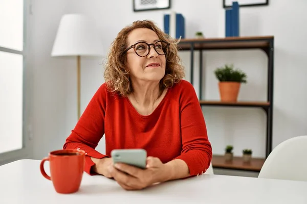 Orta Yaşlı Beyaz Kadın Akıllı Telefon Kullanıyor Evdeki Kanepede Oturup — Stok fotoğraf